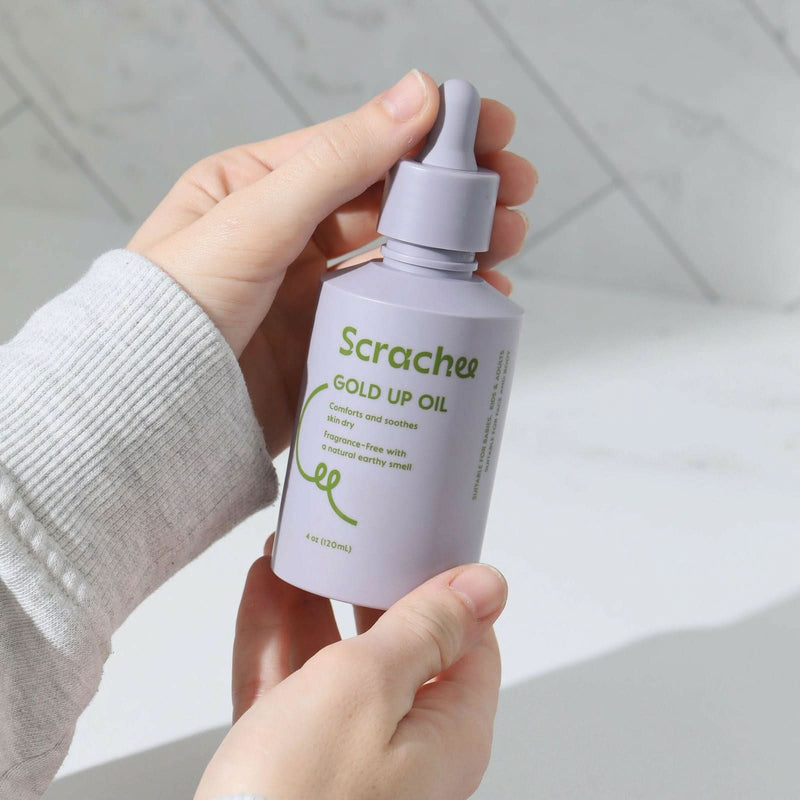 Someone holding Scrachee's Gold Up Oil in her hands.